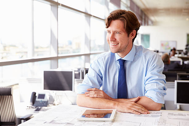 istock Male architect at his desk in an office, looking away 487808092