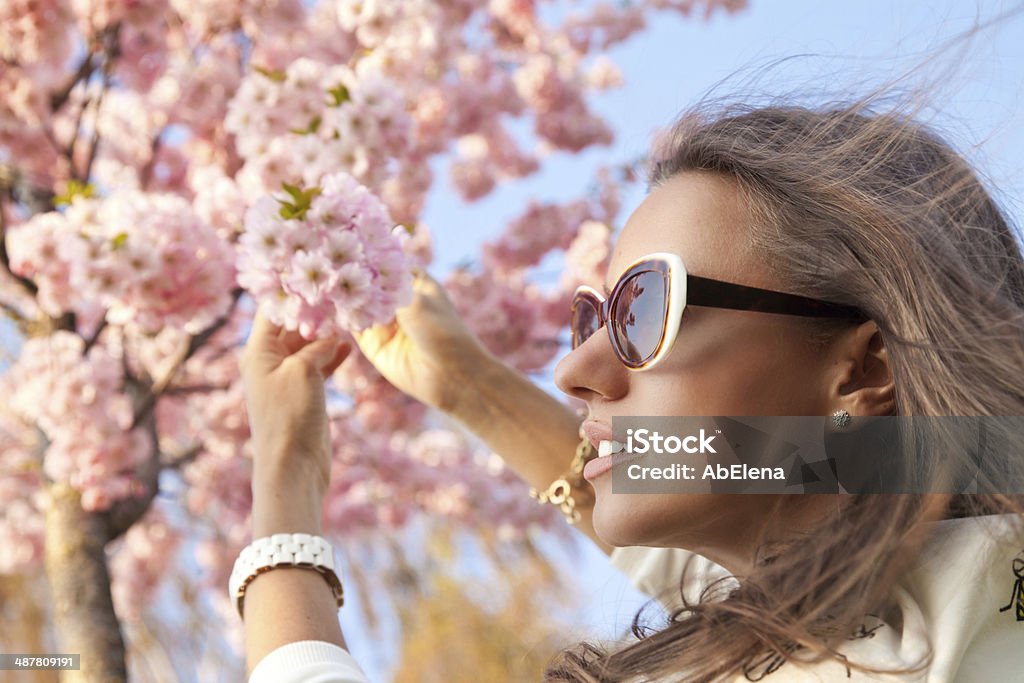 beautiful girl standing among the branches of cherry blossoms Beautiful girl outdoors spring portrait, young woman with sakura. Spring concept. Beautiful People Stock Photo