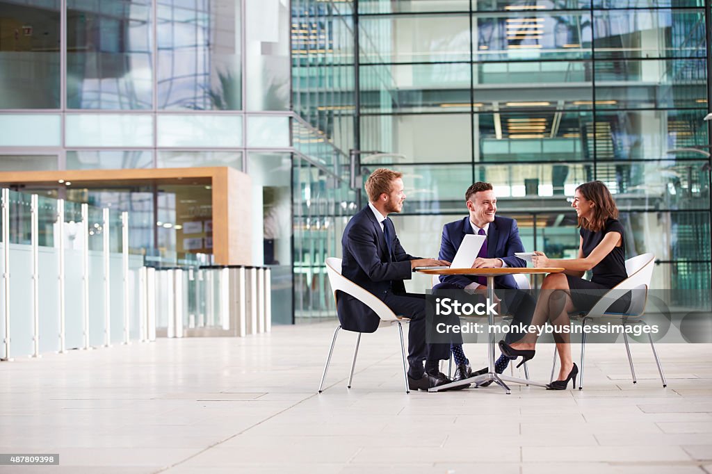 Three colleagues at a meeting in the foyer of business Three colleagues at a meeting in the foyer of a big business Three People Stock Photo