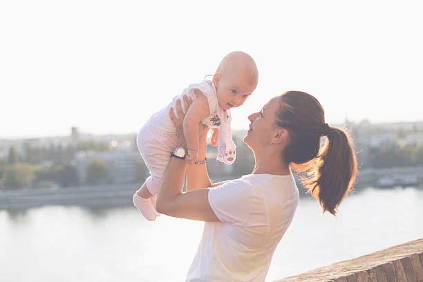 istock baby enjoys in her mother's hands on a beautiful day 487810706