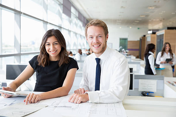istock Two young architects working in an office, smiling to camera 487813880