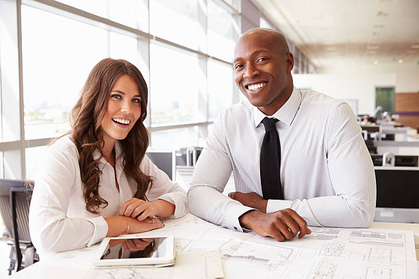 istock Male and female architects at work, looking to camera 487814432