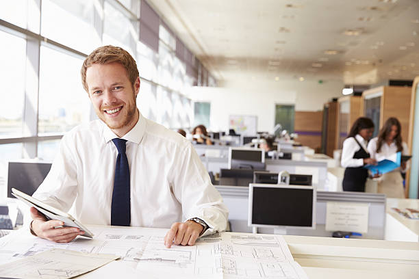 istock Young architect at work in an office, smiling to camera 487814848