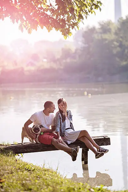 Couple sharing an intimate moment with pug-dog in the park