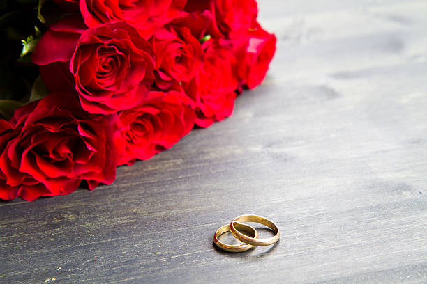 istock valentine's day Red roses and wedding ring  a wooden background 487825282
