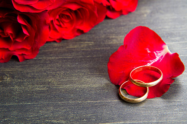 istock valentine's day Red roses and wedding ring  a wooden background 487825296