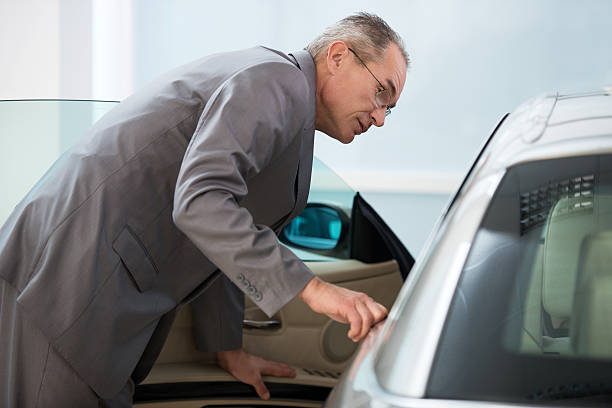 istock Mature businessman examining new car. 487825698