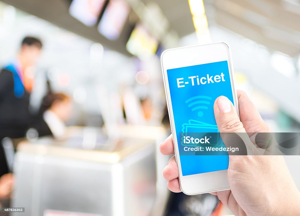 Hand holding mobile with E-Ticket with blur airport check-in bac Hand holding mobile with E-Ticket with blur airport check-in background, Digital Booking concept. Mobile Phone Stock Photo