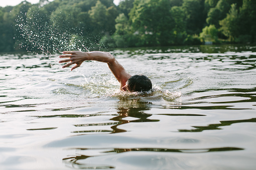 Young man swimming in a lake in Berlin's surroundings