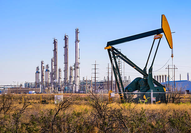 pumpjack (aceite derrick) y la planta de refinería en el oeste de texas - pozo de petróleo fotografías e imágenes de stock