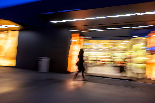 istock Motion Blurred Female Shopper Entering Illuminated Store at Dusk 487830482
