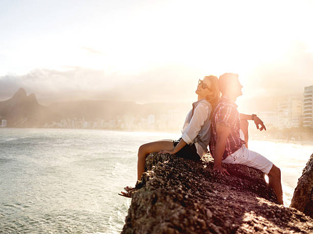 istock Couple sitting back to back on a rock at sunset. 487830780