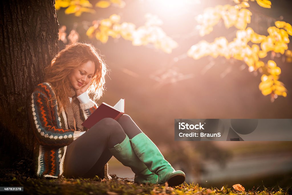 Lächelnde Frau Genießen Sie im Herbst Tag, während Sie ein Buch lesen. - Lizenzfrei Herbst Stock-Foto