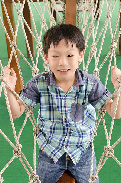istock boy climbing rope on playground 487831500