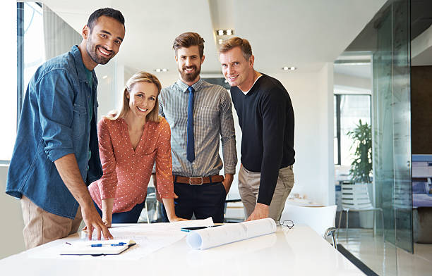 They're getting it done as a team Shot of four coworkers smiling at the camera while going over some planshttp://195.154.178.81/DATA/i_collage/pu/shoots/784351.jpg organized group photos stock pictures, royalty-free photos & images