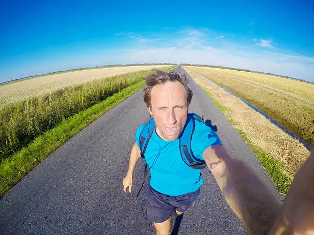 A male jogger, jogging exhausted on a rural tarr road in Schleswig-Holstein, Germany. GoPro Hero 4 black edition image.
