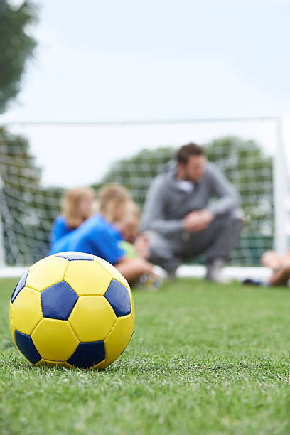 istock Coach  And Team Discussing Soccer Tactics With Ball In Foregroun 487839532
