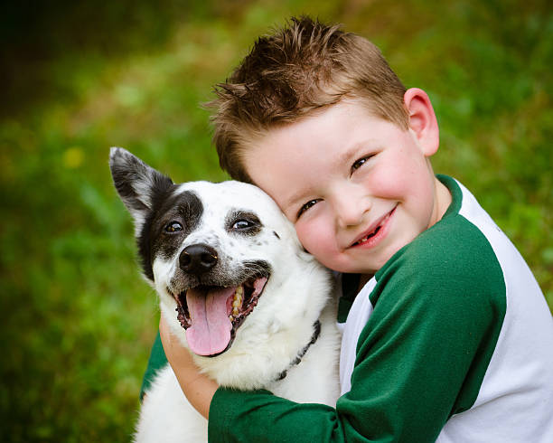 Child lovingly embraces his pet dog stock photo