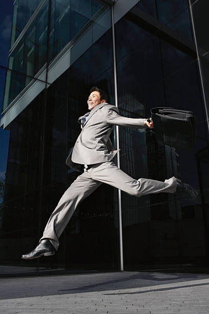 istock Businessman With Briefcase Jumping Outside Office 487854957
