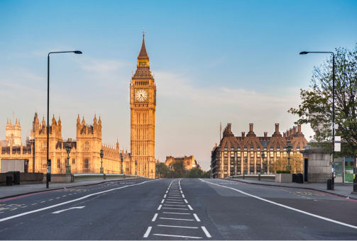 The Houses of Parliament, the Big Ben and Westminster Bridge in London at dawn. Available space for copy on the sky and on the empty road.