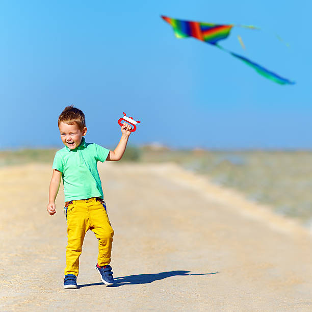 istock happy kid playing with kite on summer field 487857461