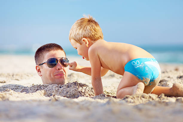 vater und sohn spaß im sand am strand - lifestyles child beach digging stock-fotos und bilder