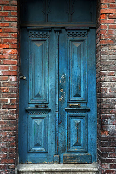 Small hobbit door in a stoned wall. Building exterior. Faded, light, sunny hipster colors.
