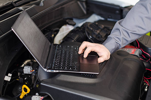 istock Mechanic with laptop diagnoses car in workshop. 487883643