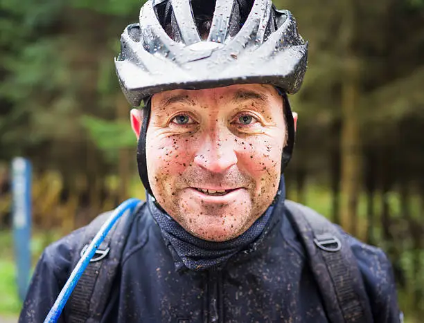 A man's face covered in muddy spots after a mountain biking session.