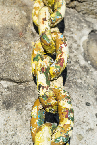 Broad chain links covered in colored layers of paint on stone background