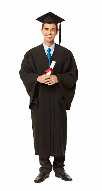 Full length portrait of young mixed race male student in graduation attire holding bachelor's degree. Vertical shot. Isolated on white.