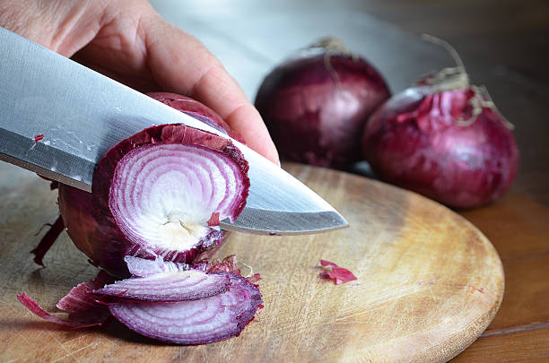 istock cutting onions with knife on cutting board 487910482