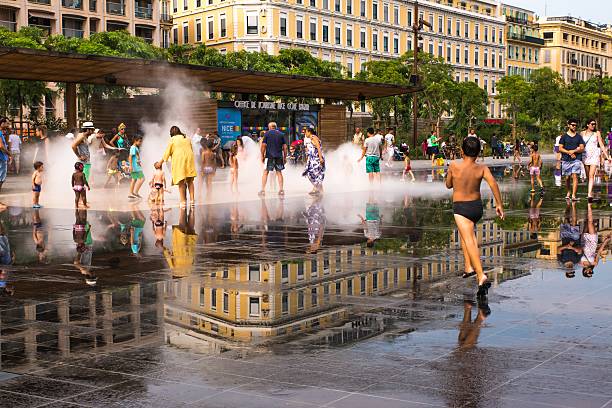 Nice, France - August 13, 2015: Children play in public water feature. The new fountain in the heart of Nice, officially is opened in October 2013. The water springs unexpectedly and many people like this fountain to cool off especially during the hot summer days in Nice.