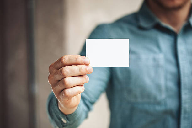 istock Man holding white business card on concrete wall background 487911276