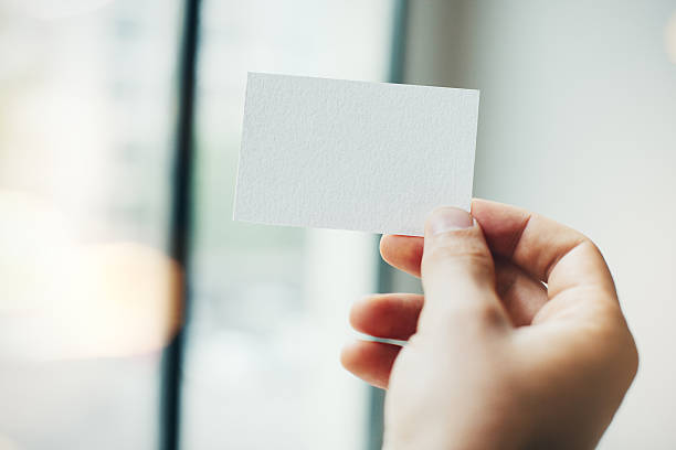istock Man's hand with white business card on the blurred 487912044
