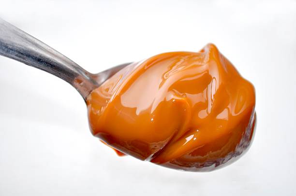 milk caramel Spoon with dulce de leche on a white background dulce de leche stock pictures, royalty-free photos & images