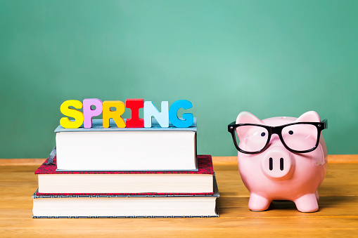 Spring Semester theme with textbooks and piggy bank and green chalkboard