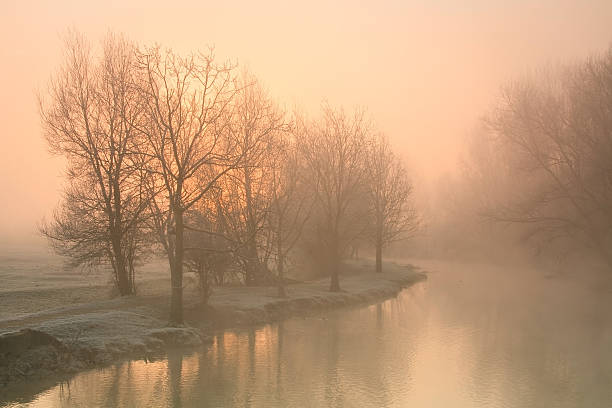 Dramatic sunrise burning through fog over a lake adjacent to the grand stands for observing rowing competitions.