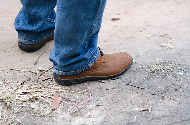 istock Human foot with brown leather shoes and jeans 487923629