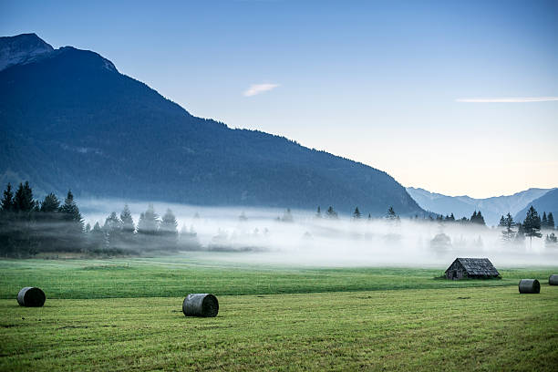 Little hut and bays of straw in foggy mountains stock photo