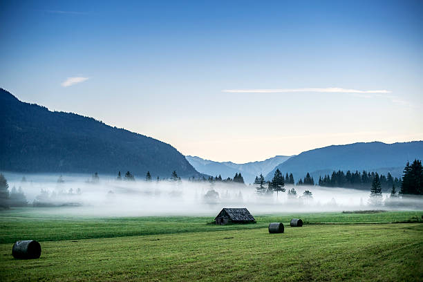 Little hut and bays of straw in foggy mountains stock photo