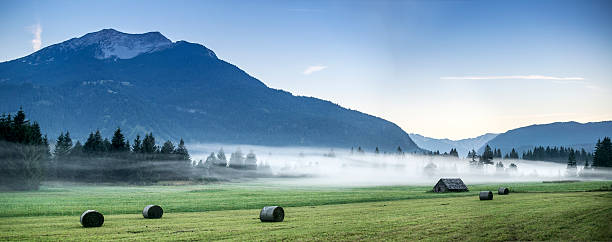 Little hut and bays of straw in foggy mountains stock photo