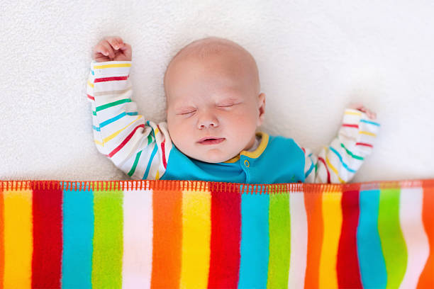 pequeno bebê menino dormir sob o cobertor colorida - newborn little girls baby lying down - fotografias e filmes do acervo