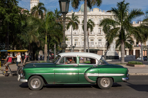 Havana, Сuba - June 11, 2014: A green classic american car passing by Parque Central in Old Havana.