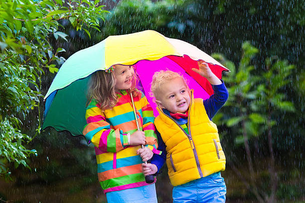 istock Kids playing in the rain under colorful umbrella 487926084