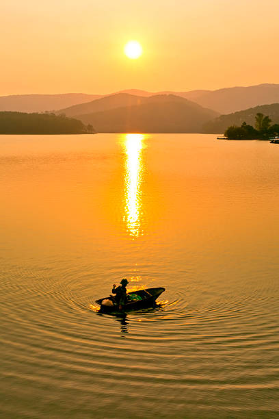 istock Fishing boat in golden lake at sunnet 487940320