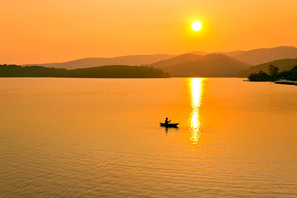 istock Fishing boat in golden lake at sunnet 487940370