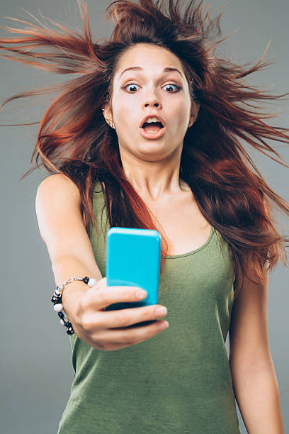 Fast Internet A girl holding a smart phone amazed by her powerful internet. windspeed stock pictures, royalty-free photos & images