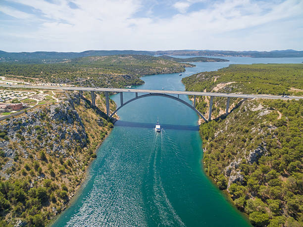 Motorway bridge over Krka river with boat sailing beneath, Croatia