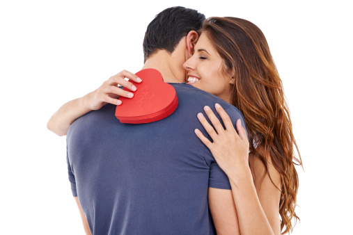 Studio shot of a young woman embracing her boyfriend while holding a heart